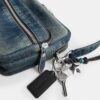 Dakota-crossbody-veske i regenerativ bomullsdenim med anheng