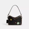 Rexy 10-årsdag Dakota-crossbody-veske i «Loved Leather» med klistremerketrykk